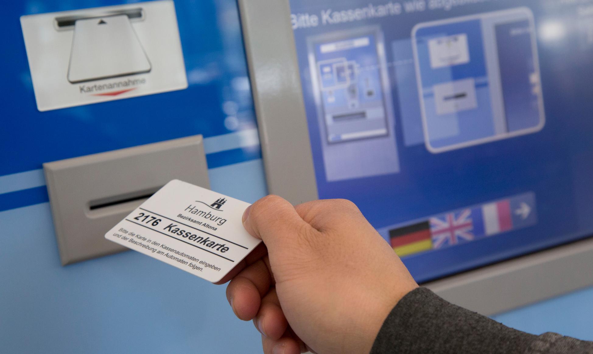 Eine Person führt eine Kassenkarte zum Geldautomaten der Behörde in Hamburg