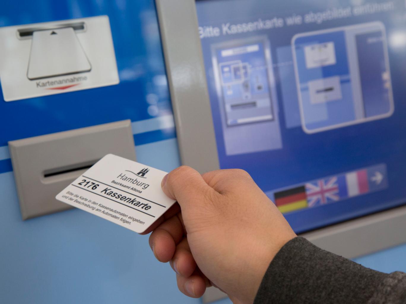 Eine Person führt eine Kassenkarte zum Geldautomaten der Behörde in Hamburg