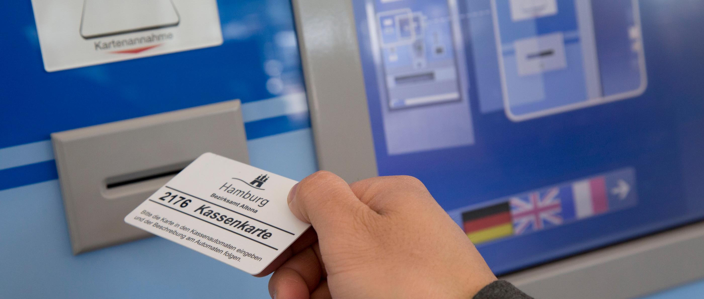 Eine Person führt eine Kassenkarte zum Geldautomaten der Behörde in Hamburg