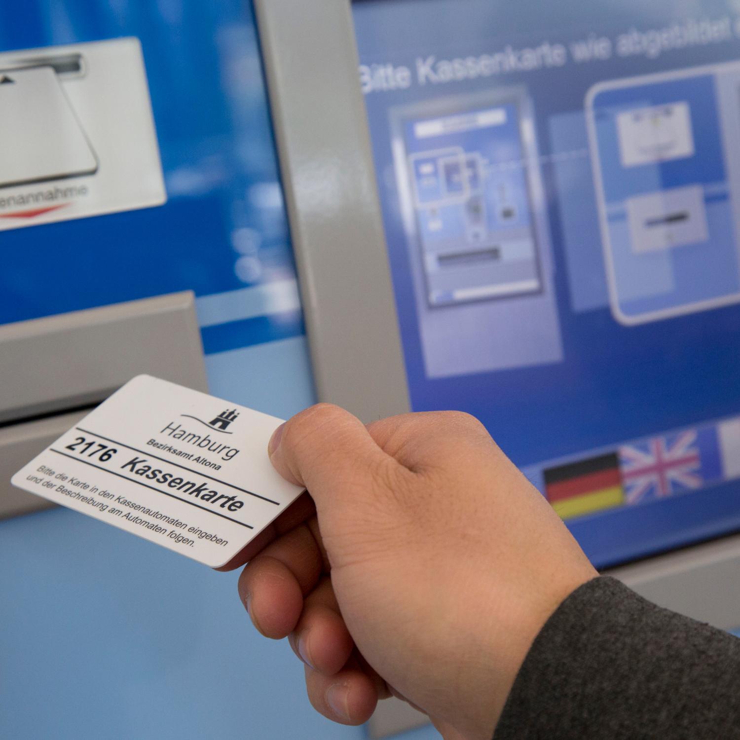 Eine Person führt eine Kassenkarte zum Geldautomaten der Behörde in Hamburg