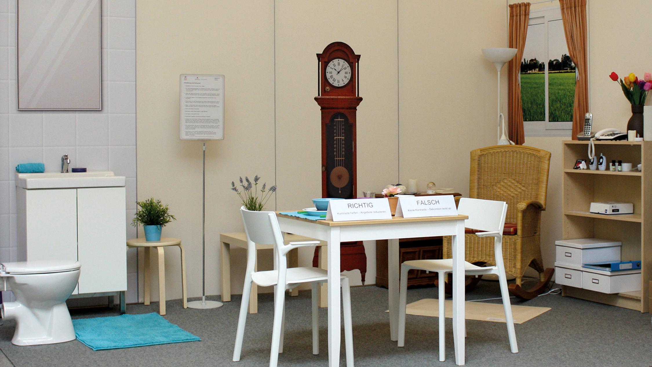 Gegenstände und Möbel des täglichen Lebens stehen mit Erläuterungen aufgebaut in der Demenzmusterwohnung