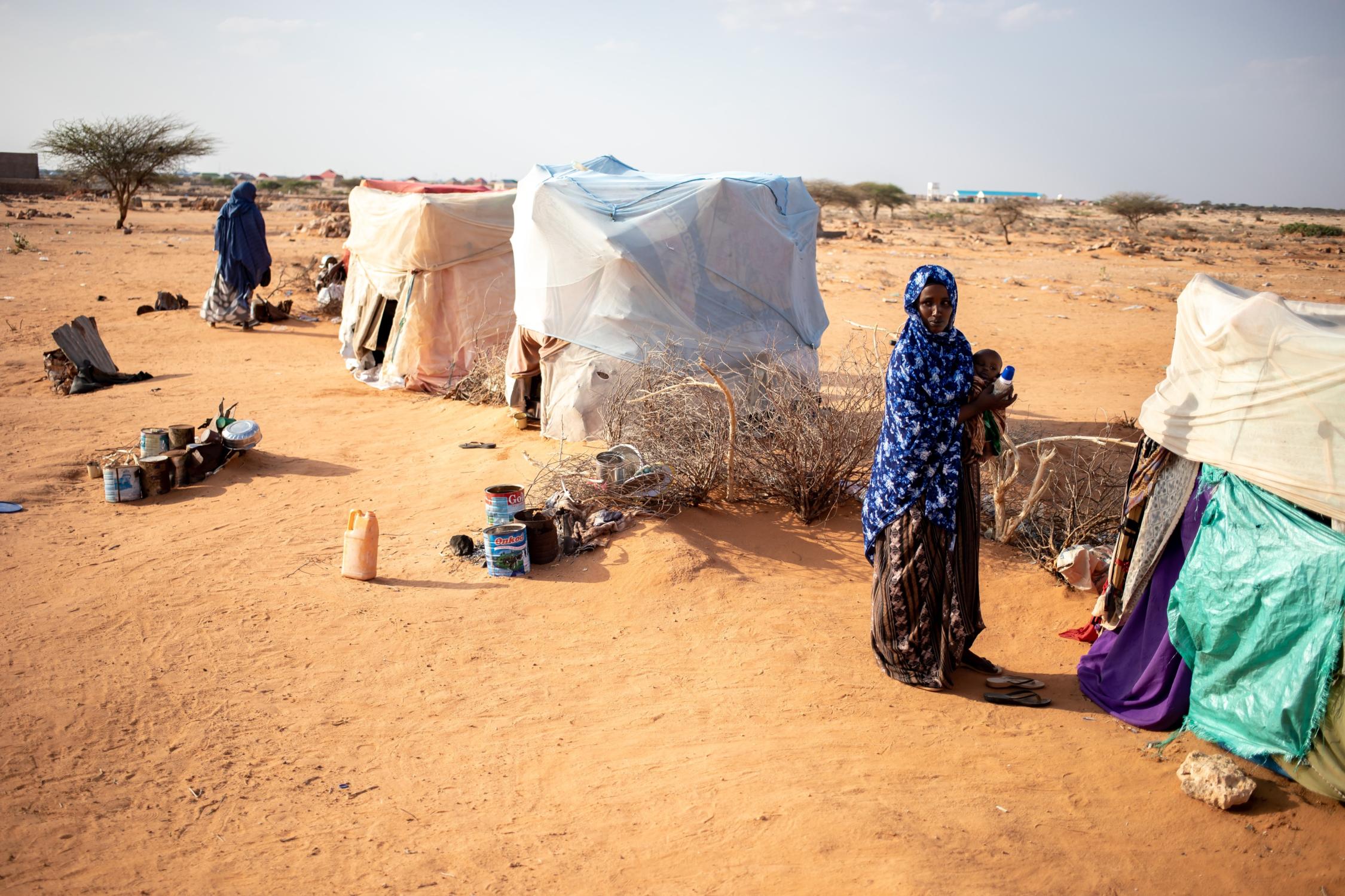 Frauen stehen vor provisorisch aufgebauten Zelten in einer Dürre-Landschaft in Somalie