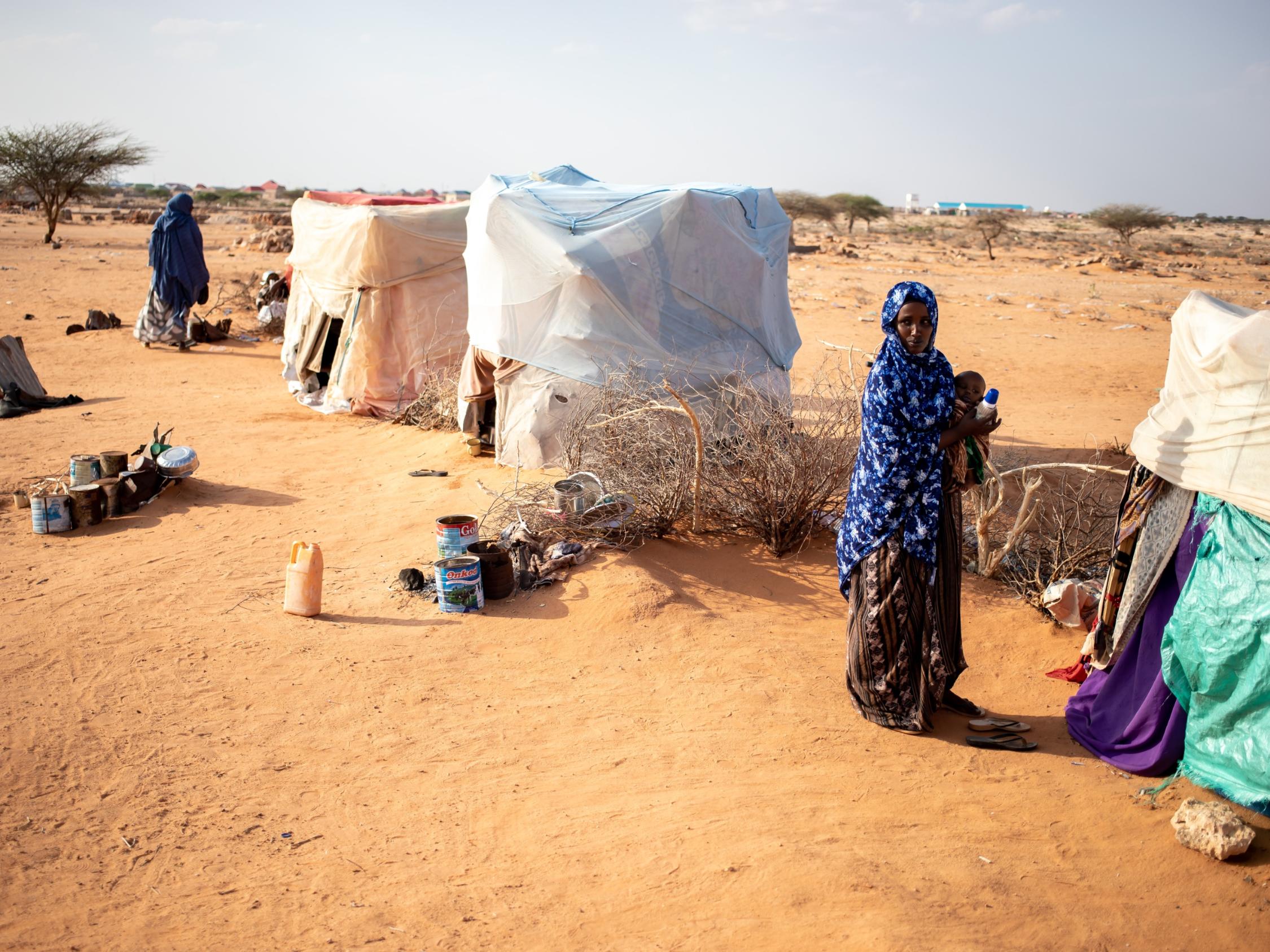 Frauen stehen vor provisorisch aufgebauten Zelten in einer Dürre-Landschaft in Somalie