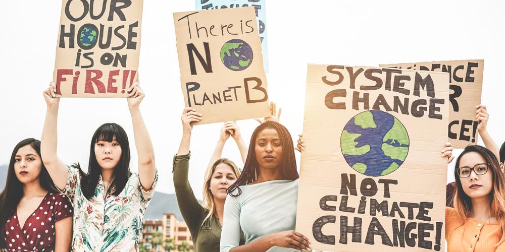 Junge Frauen halten Plakate in die Luft und demonstrieren gegen Klimawandel