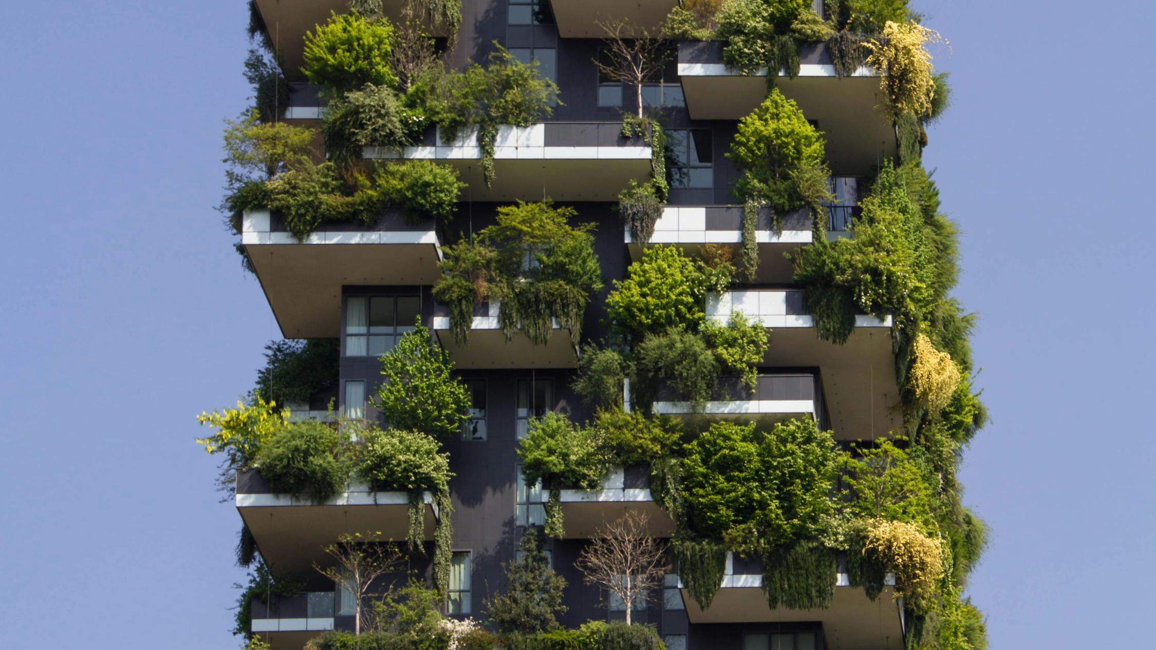 Fassade und Balkone eines Hochauses sind dicht begrünt und mit Pflanzen bestückt