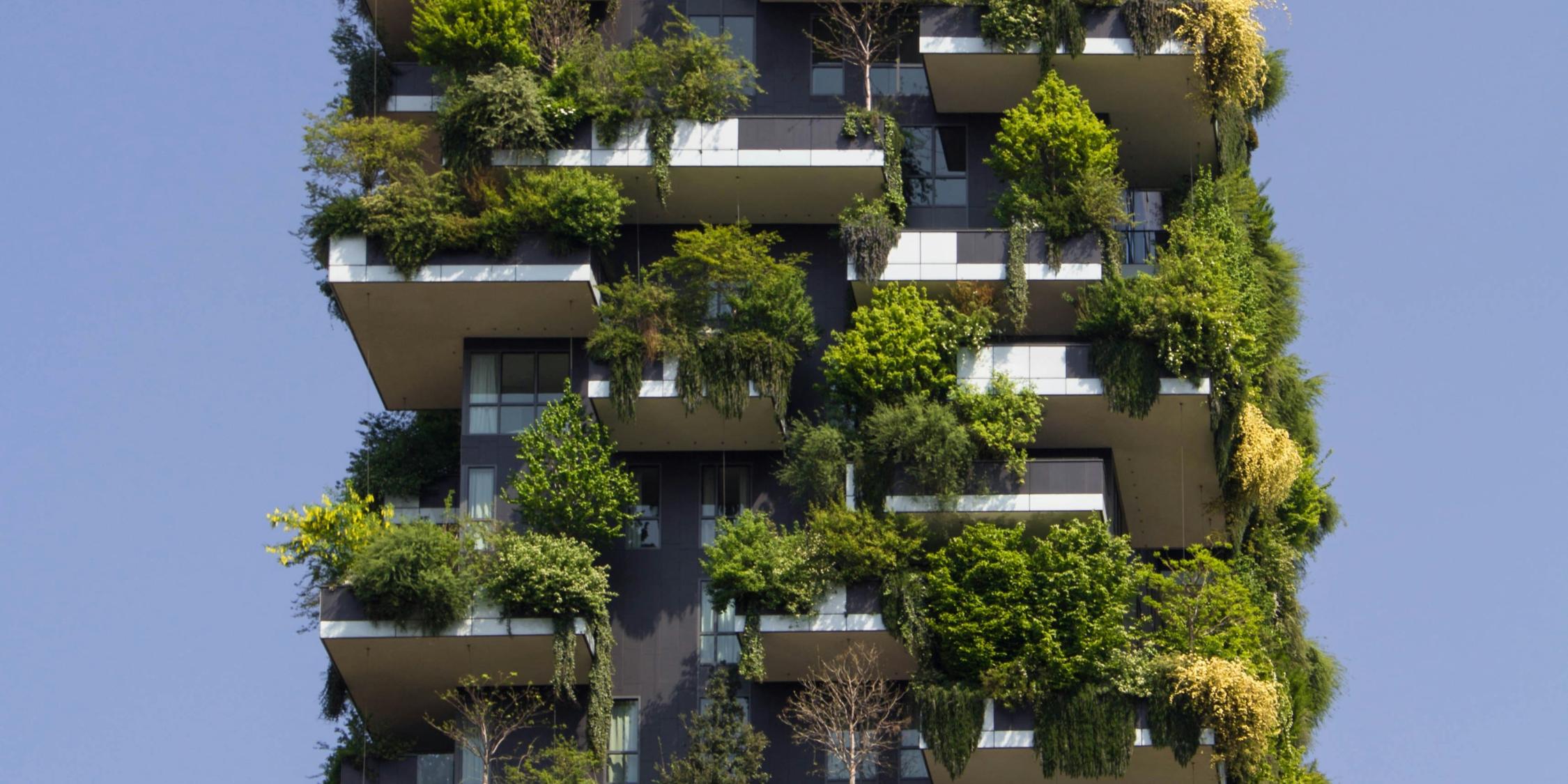 Fassade und Balkone eines Hochauses sind dicht begrünt und mit Pflanzen bestückt