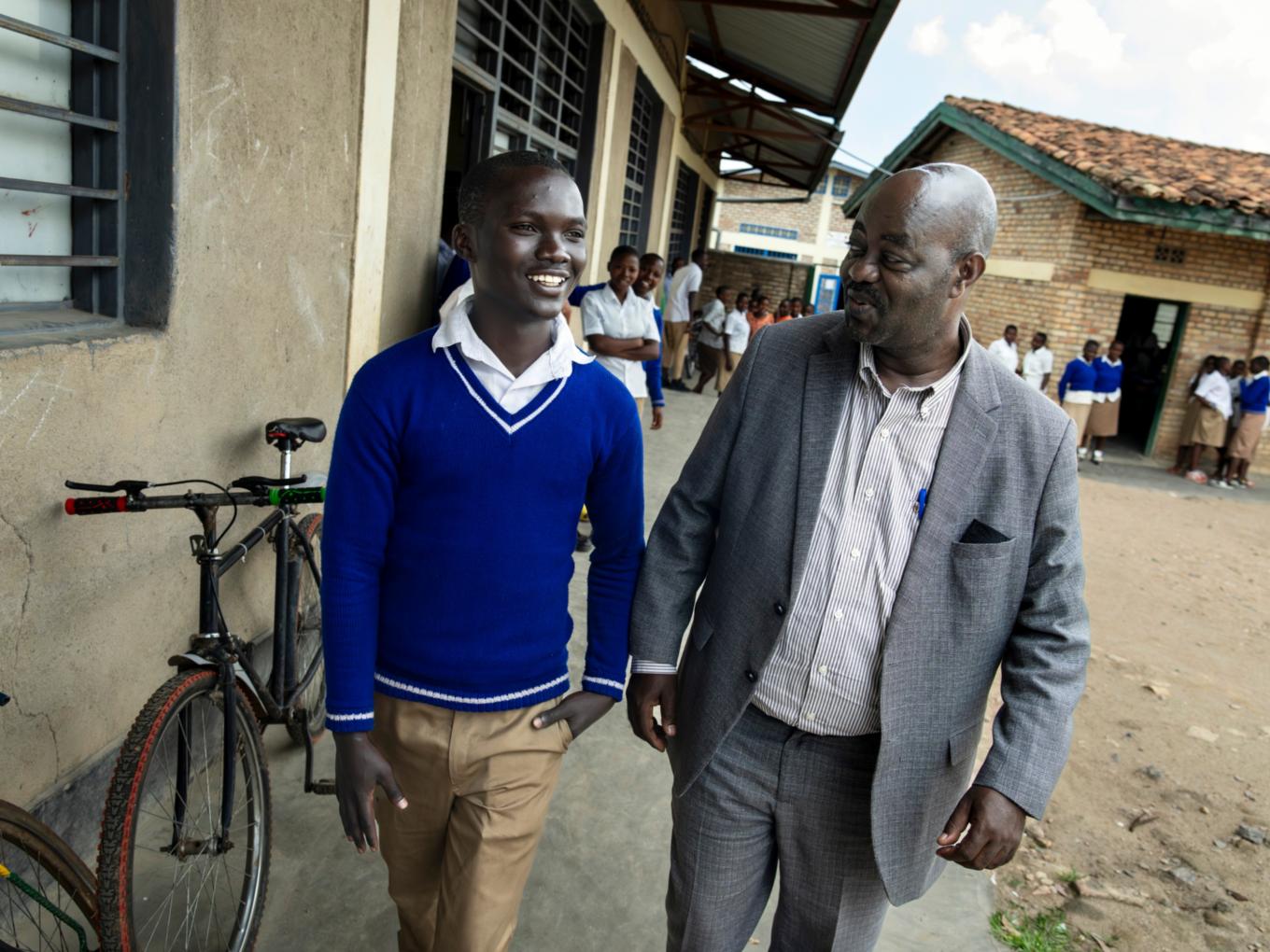 Zwei Männer gehen in Ruanda in einem Dorf an einem Haus entlang