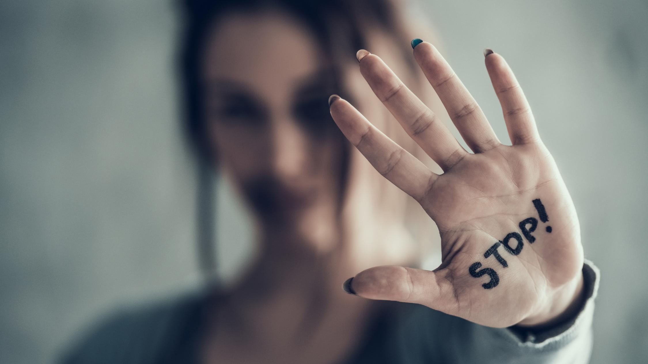 Eine Frau zeigt mit ihrer Handfläche zum Betrachter, auf der das Wort 'Stop' steht