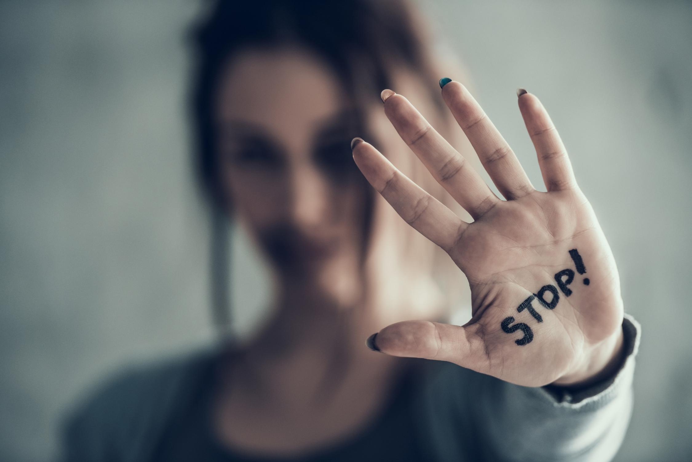 Eine Frau zeigt mit ihrer Handfläche zum Betrachter, auf der das Wort 'Stop' steht