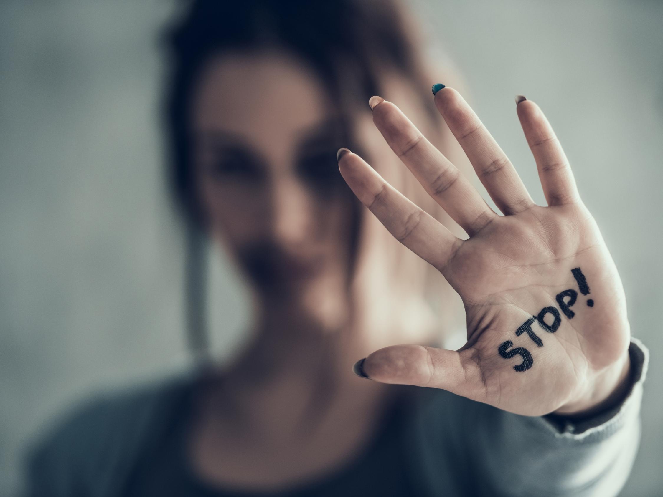 Eine Frau zeigt mit ihrer Handfläche zum Betrachter, auf der das Wort 'Stop' steht