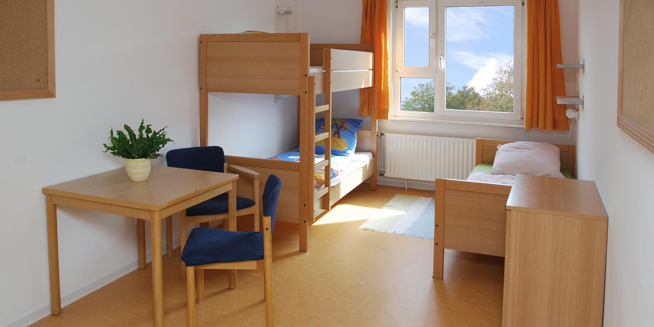 Blick in ein Zimmer mit Hochbett und Bett, Tisch und Stühlen im Frauenhaus