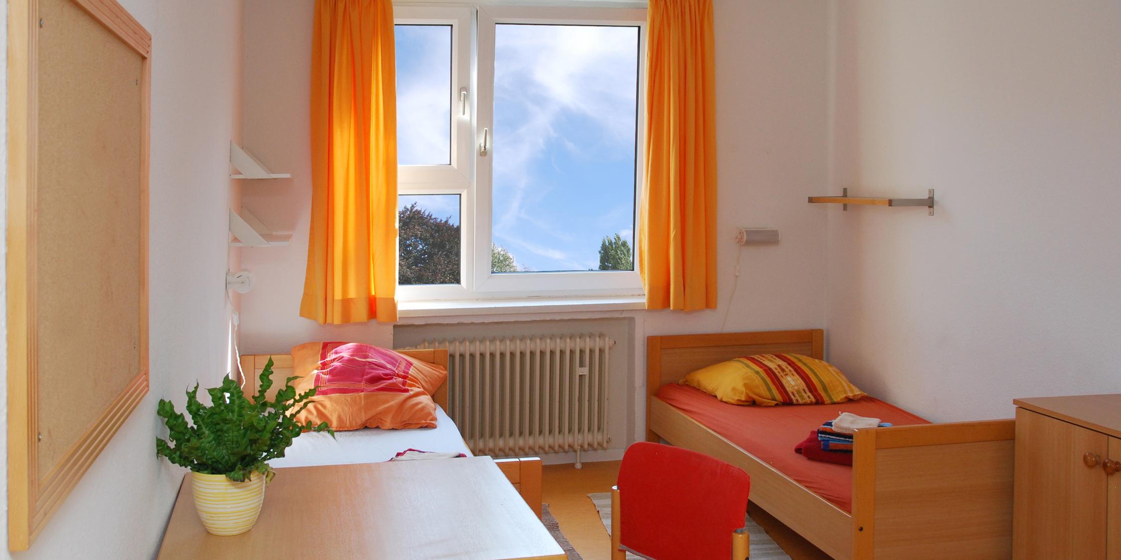 Blick in ein Zimmer eines Frauenhauses mit zwei Betten und einem Tisch mit Stuhl