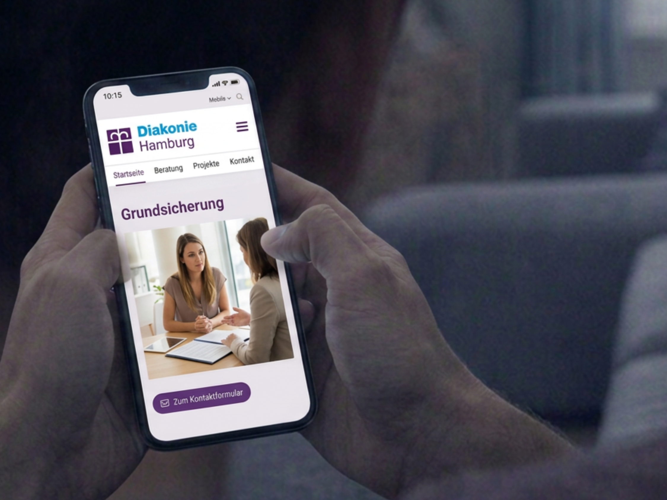 Man schaut einem Mann über die Schulter auf sein Smartphone, auf dem die Website der Diakonie Hamburg geöffnet ist.