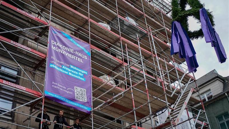 Ein Baugerüst an einem entstehenden Haus mit einem lila Banner und einem Kranz.