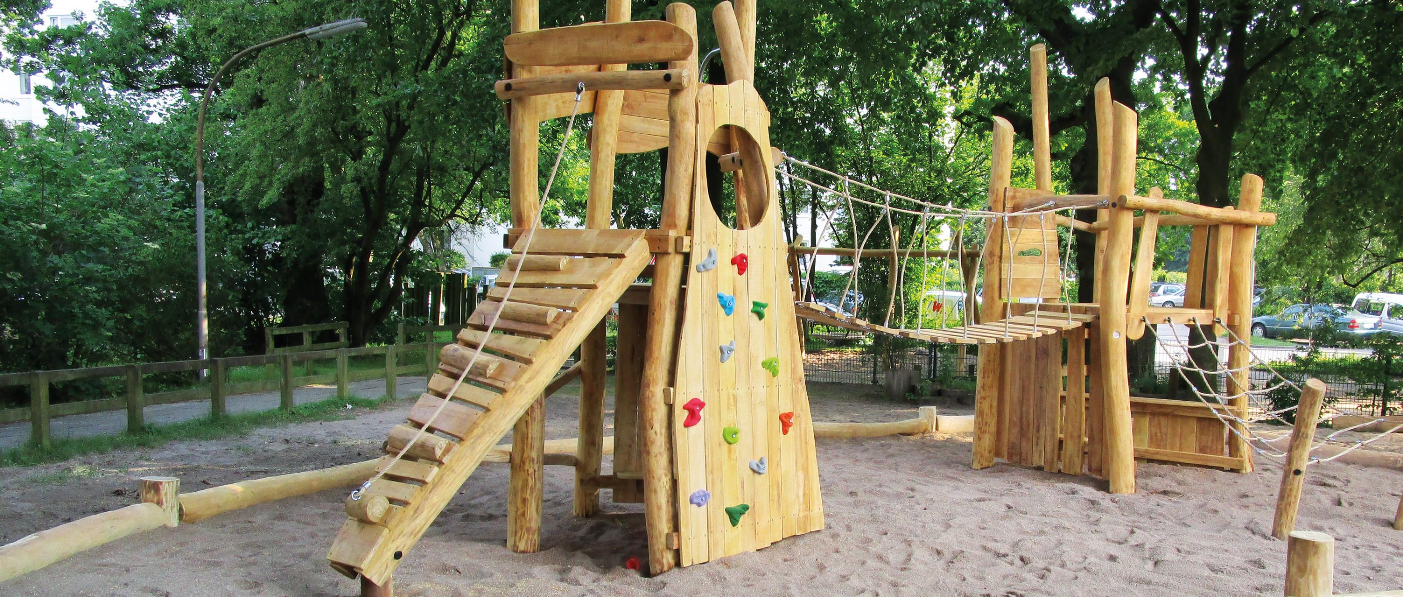 Ein Klettergerüst aus Holz in einem eingezäunten Park.