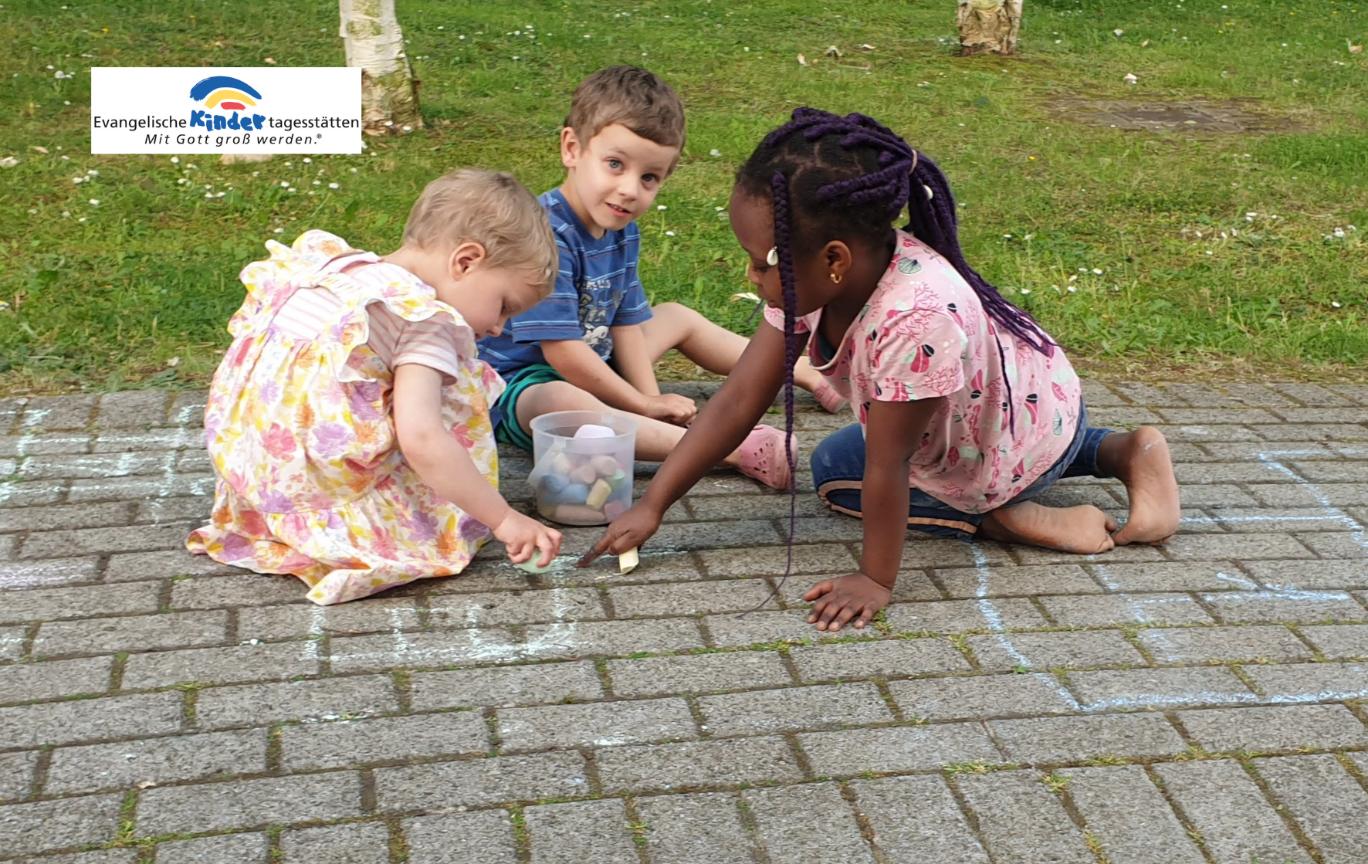 Drei Kinder sitzen auf einem gepflasterten Boden und spielen mit kleinen Gegenständen