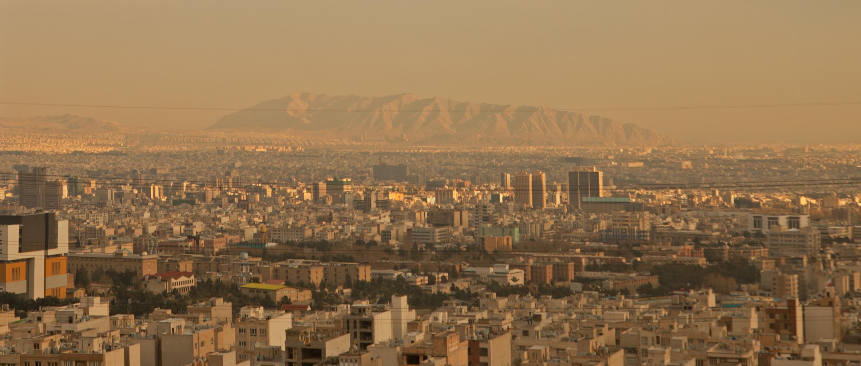 Die Skyline einer Stadt im Iran mit Bergen am Horizont.