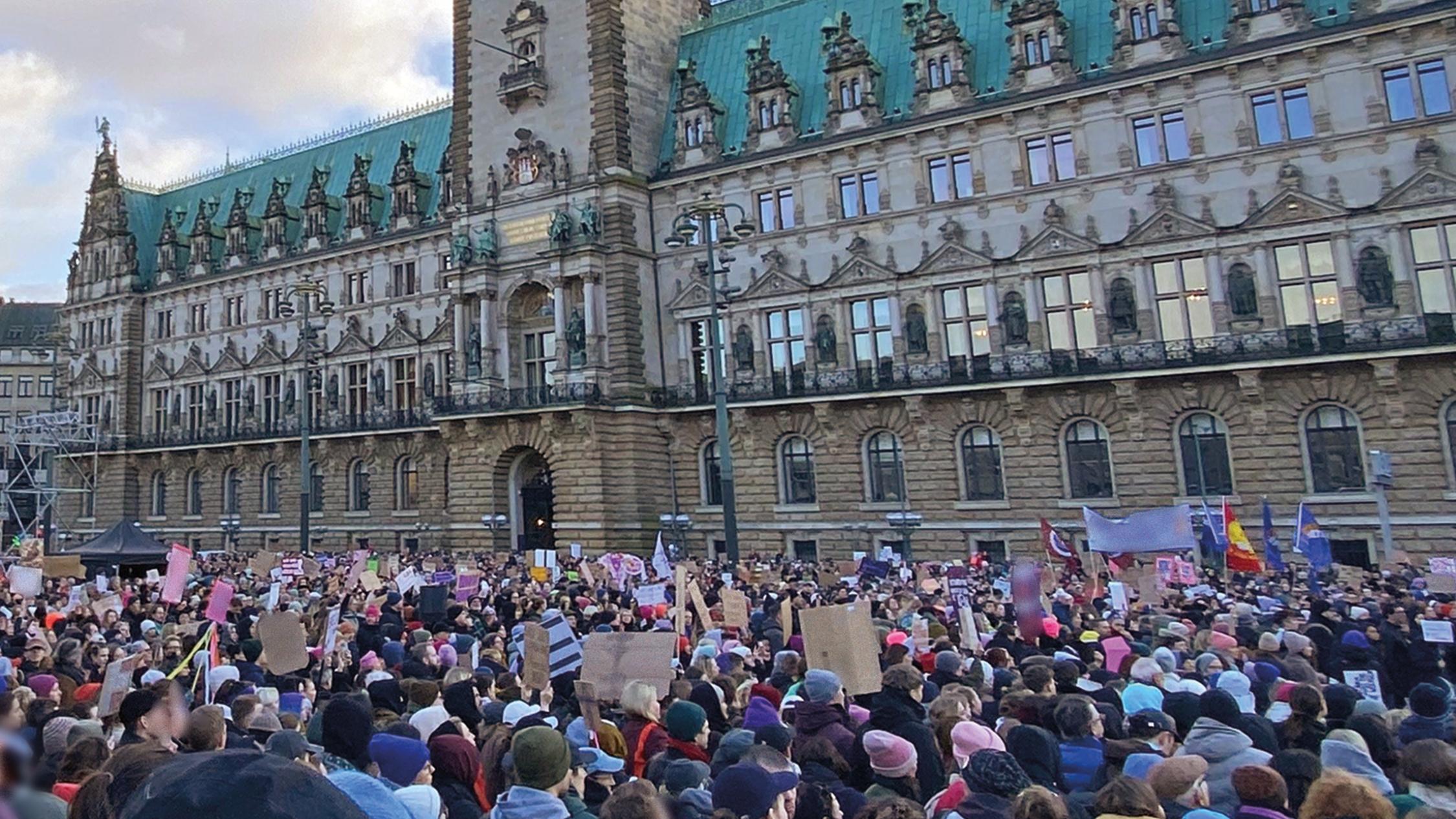 Menschen halten Plakate hoch vor dem Hamburger Rathaus