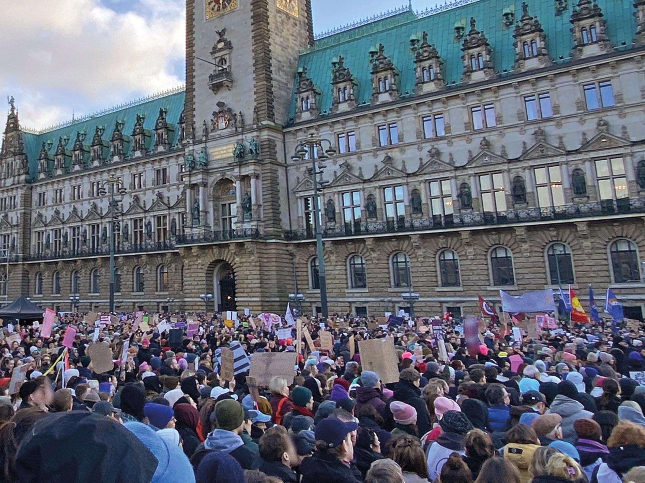 Menschen halten Plakate hoch vor dem Hamburger Rathaus