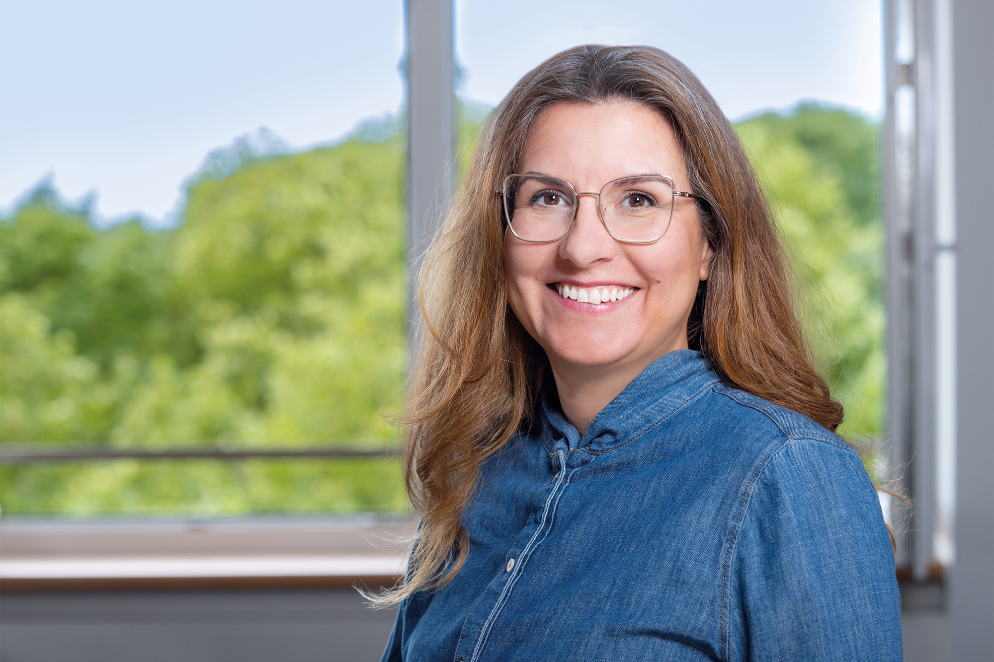 Eine Frau mit Brille lächelt in die Kamera