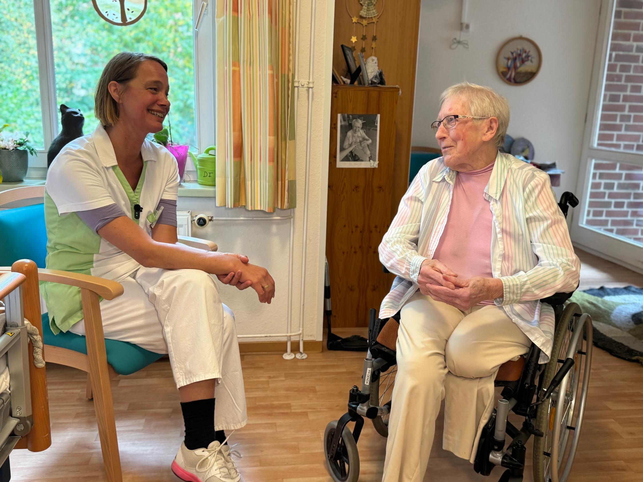 Zwei Frauen unterhalten sich und lächeln sich an.