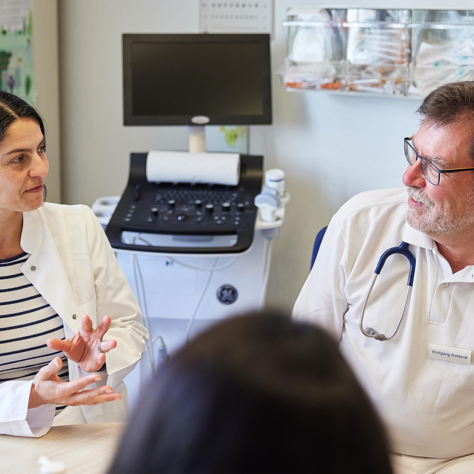Eine Ärztin und ein Arzt beraten einen Patienten