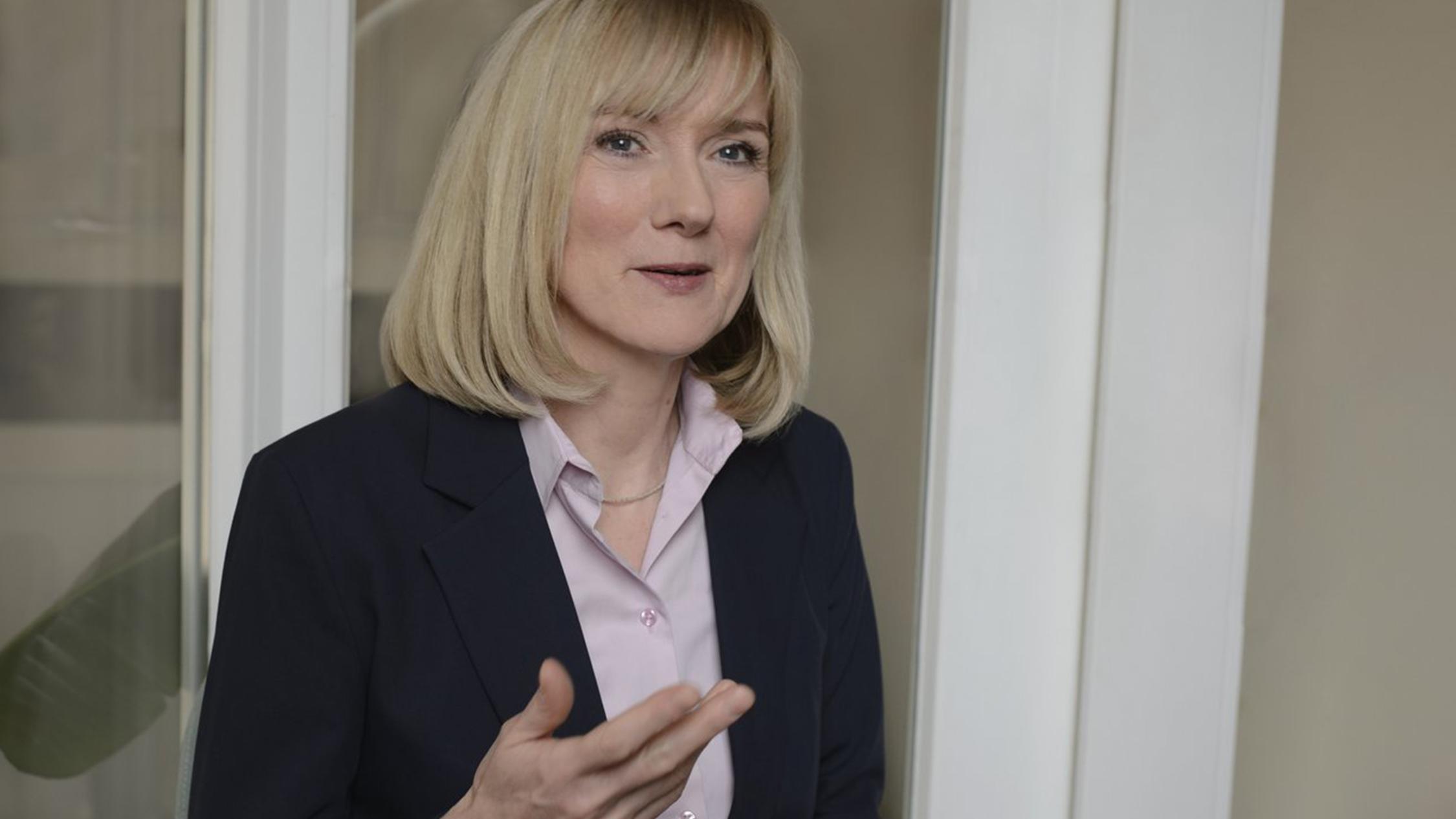 Eine Frau spricht in die Kamera und gestikuliert mit der rechten Hamd.