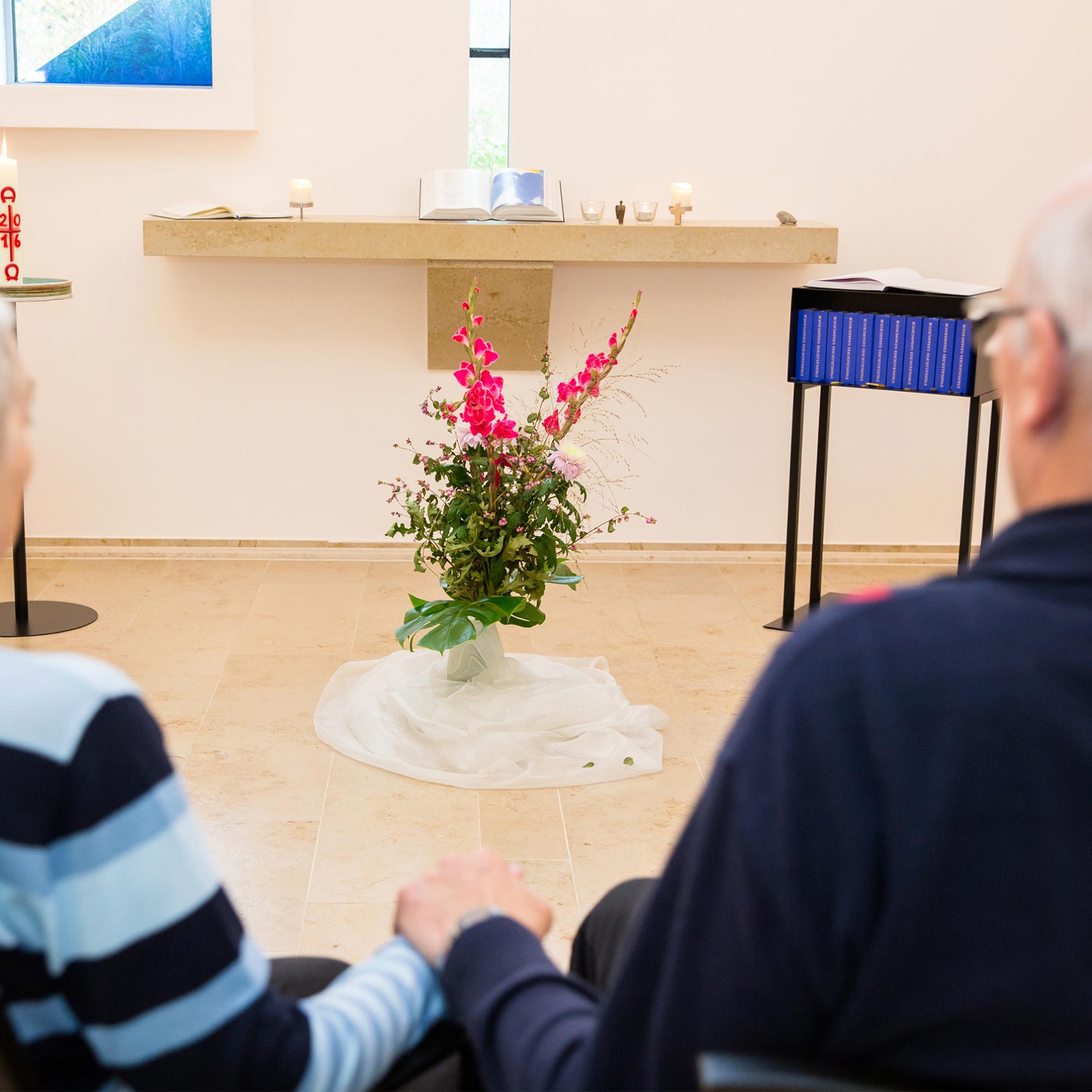 eine Frau und ein Mann beten und halten inne im Hospiz