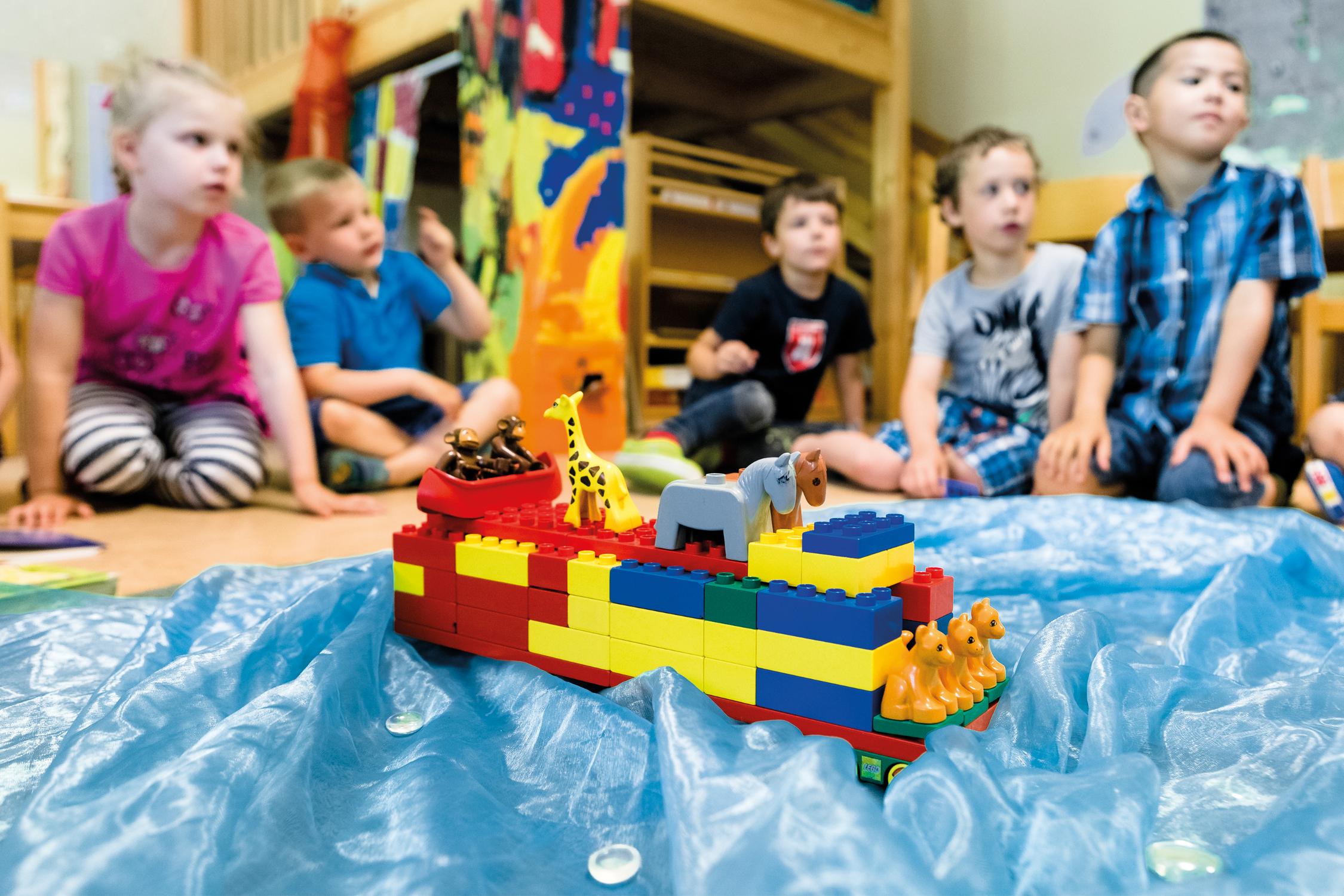 Fünf Kinder spielen auf den Fußboden mit Lego
