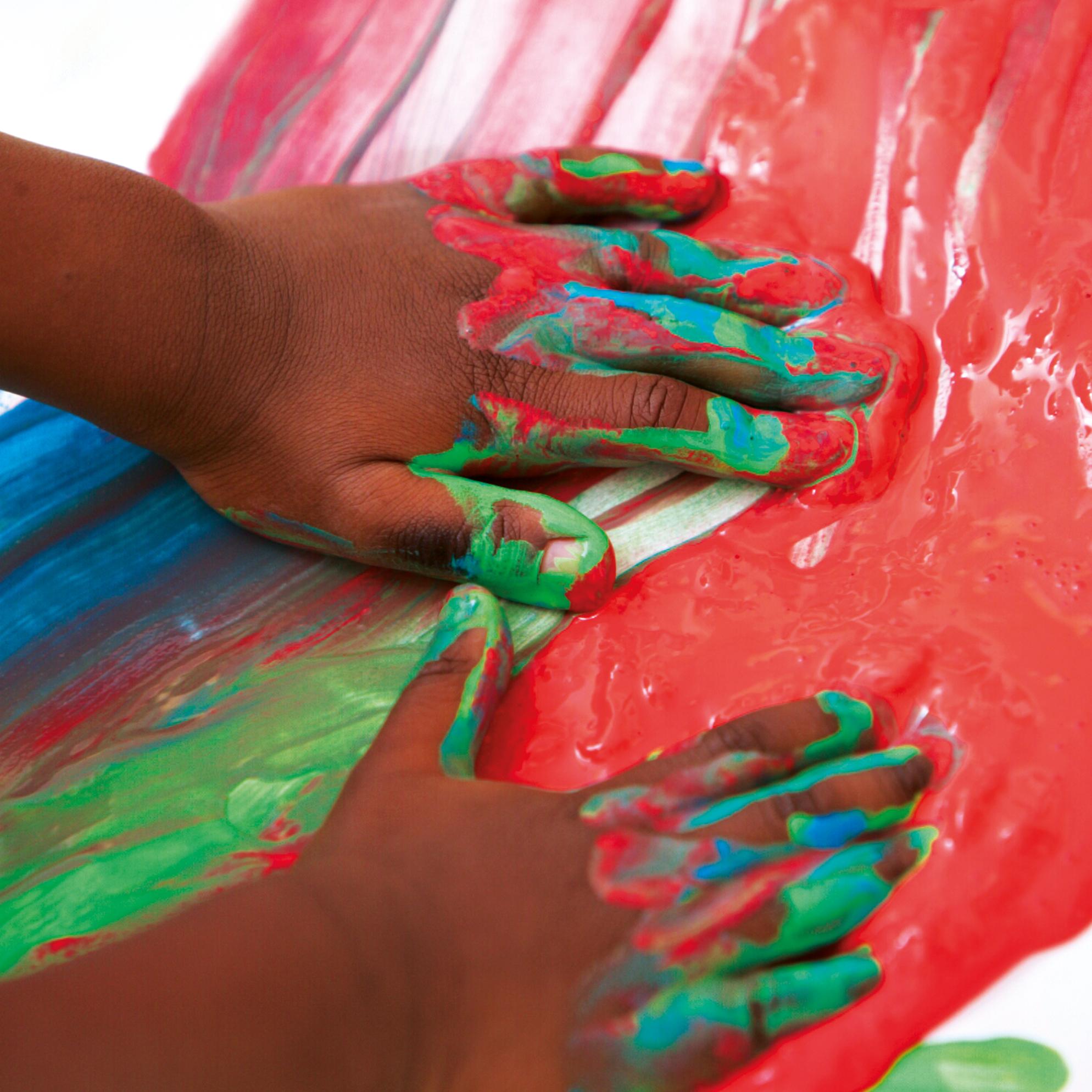 zwei Kinderhände malen mit Farben auf Papier