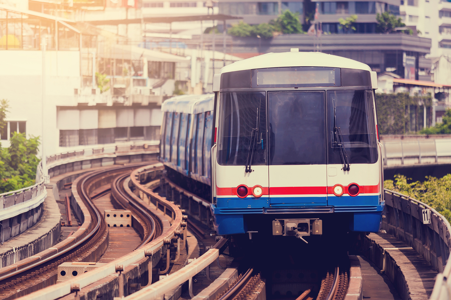 Auf Schienen fährt eine blau-weiß-rote Bahn der Kamera entgegen.