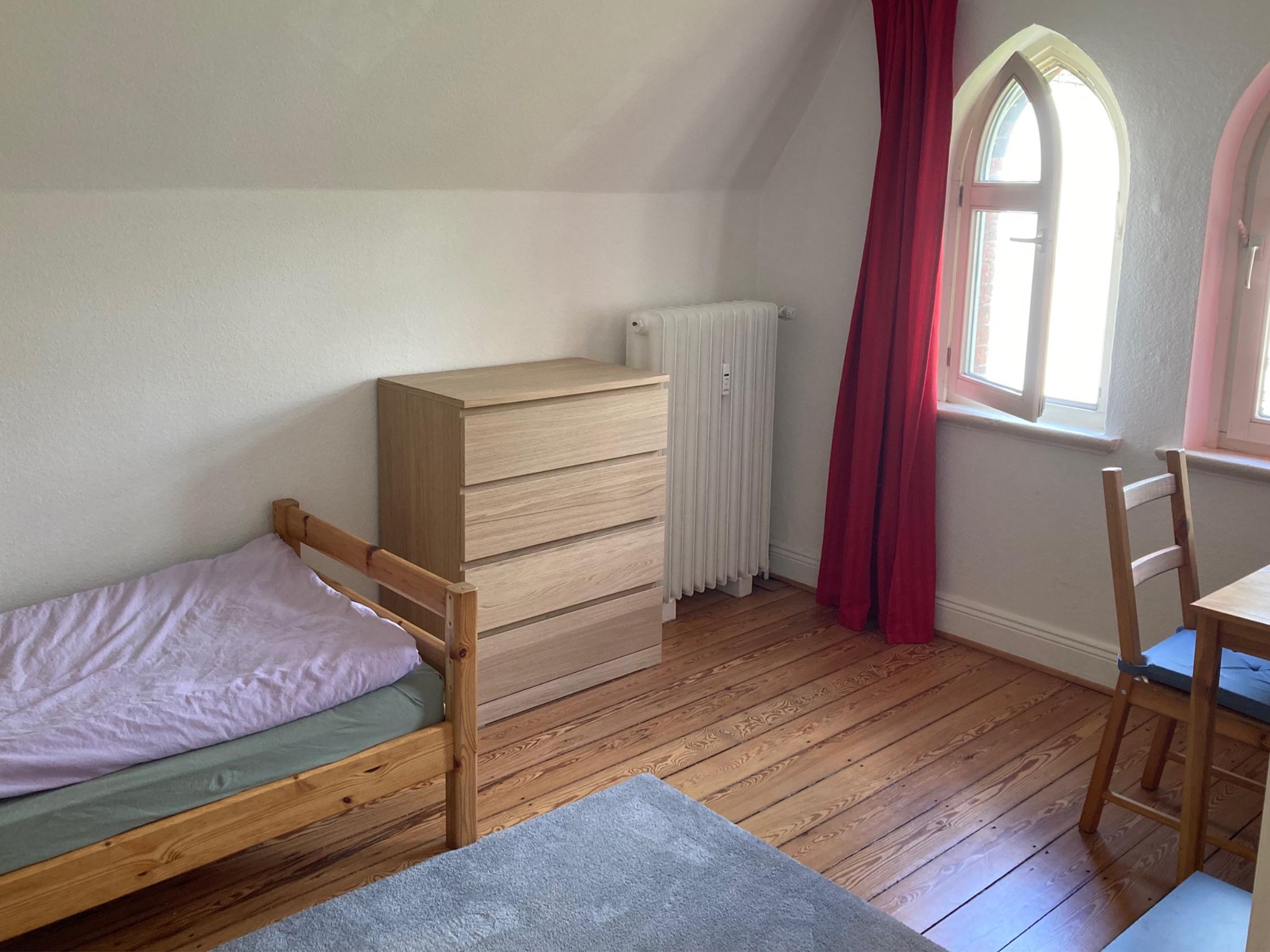Ein Zimmer mit Bett, Kommode, Stuhl und Tisch
