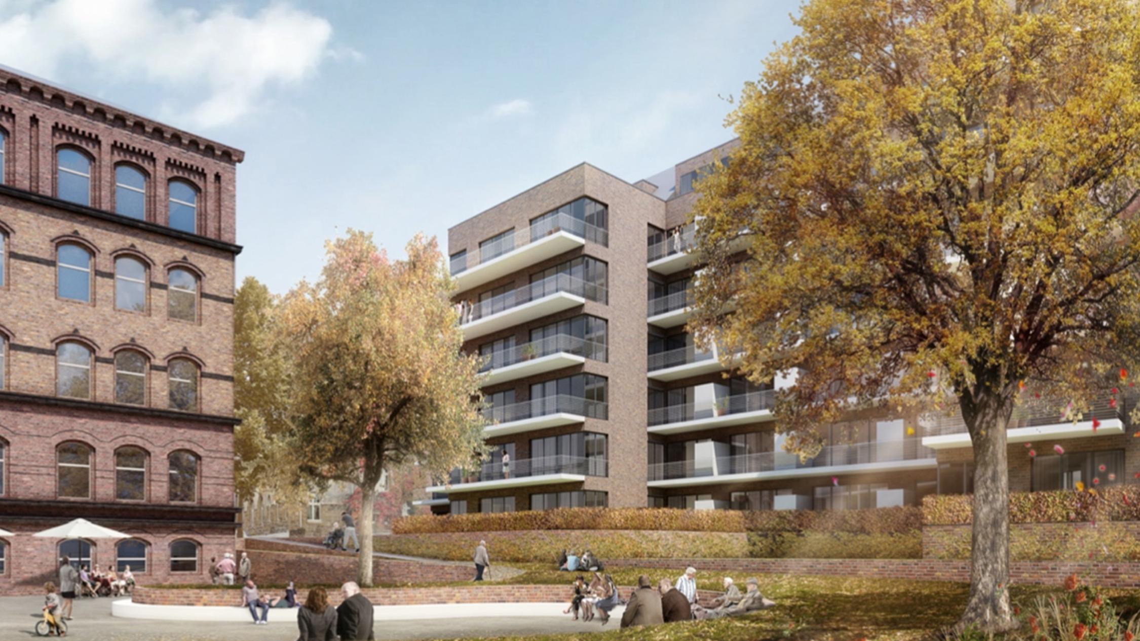 Zwischen rötlichen Gebäuden mit mehreren Wohnungen liegt ein Park, in dem sich viele Menschen aufhalten.
