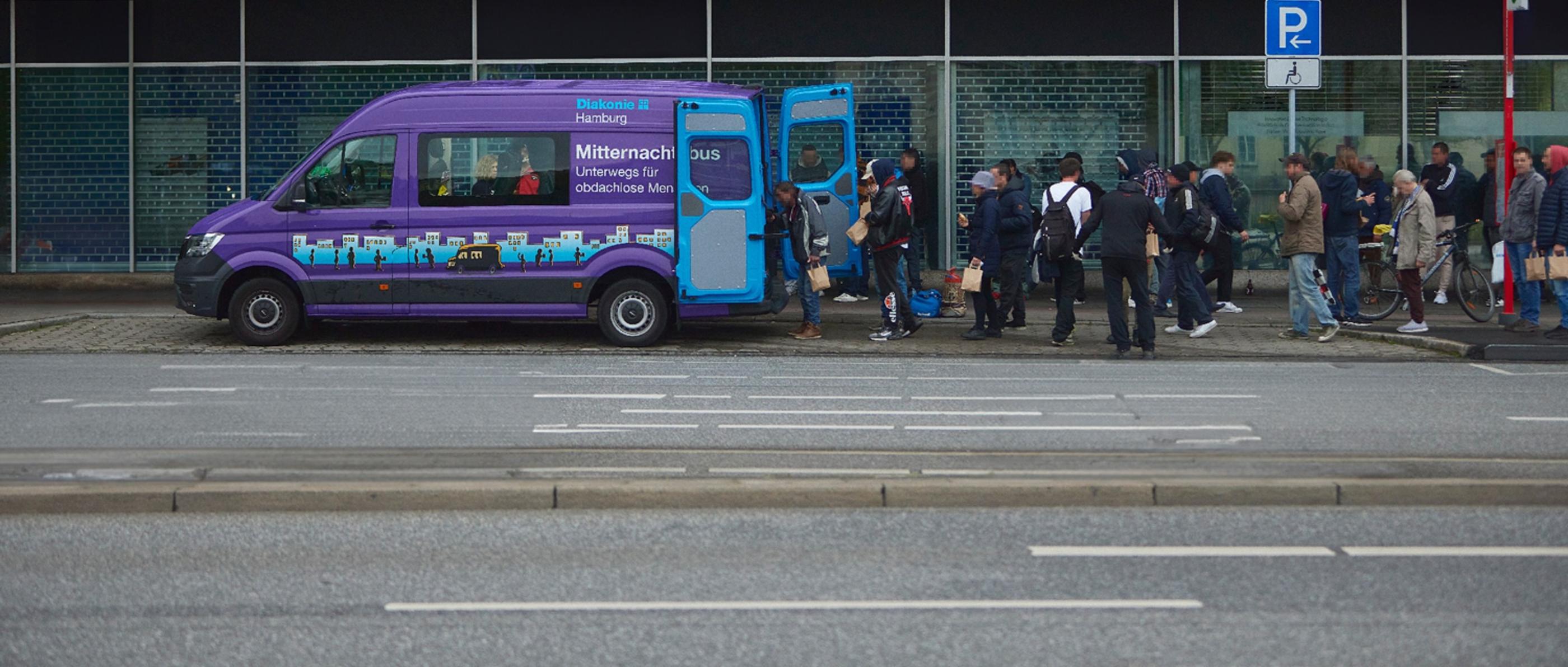 Der Bus der Diakonie parkt am Straßemnrand, Menschen stehen in einer Schlange für die Ausgabe