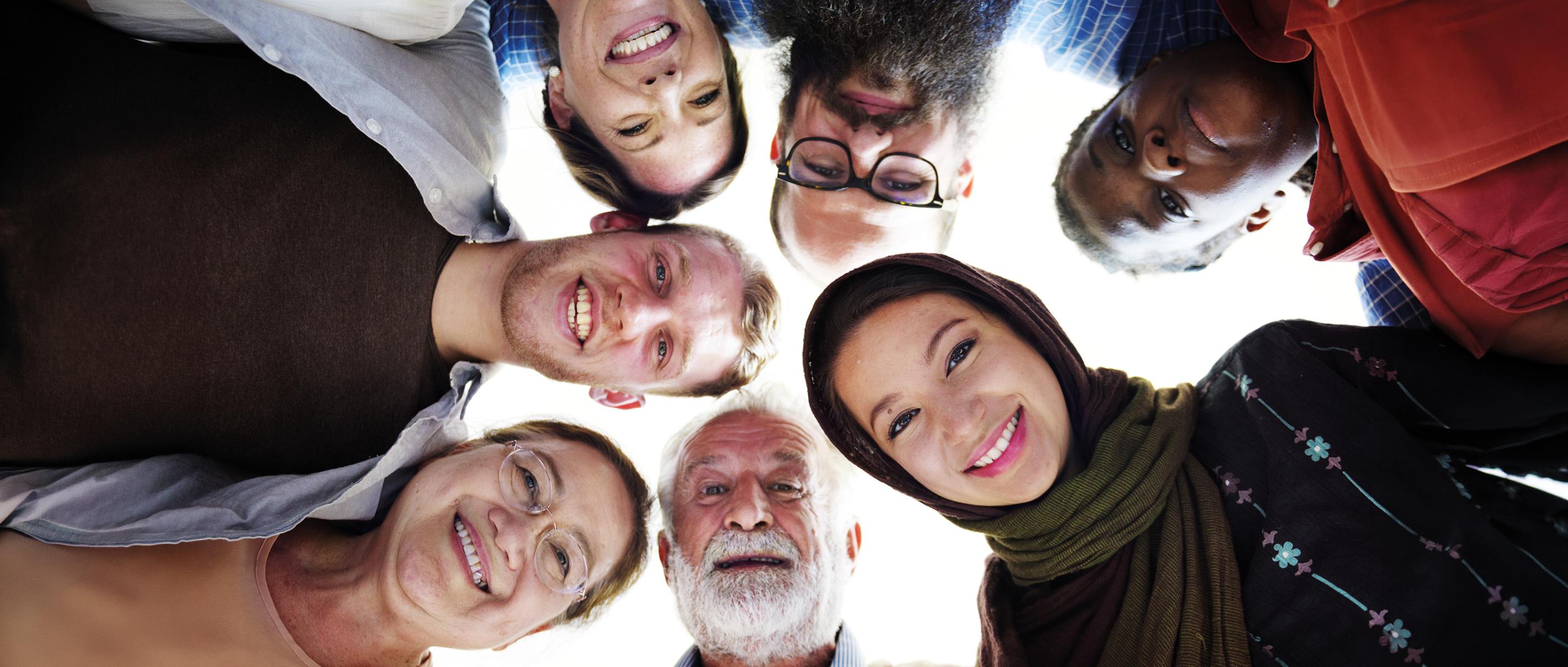 Verschiedene Menschen schauen von oben in die Kamera