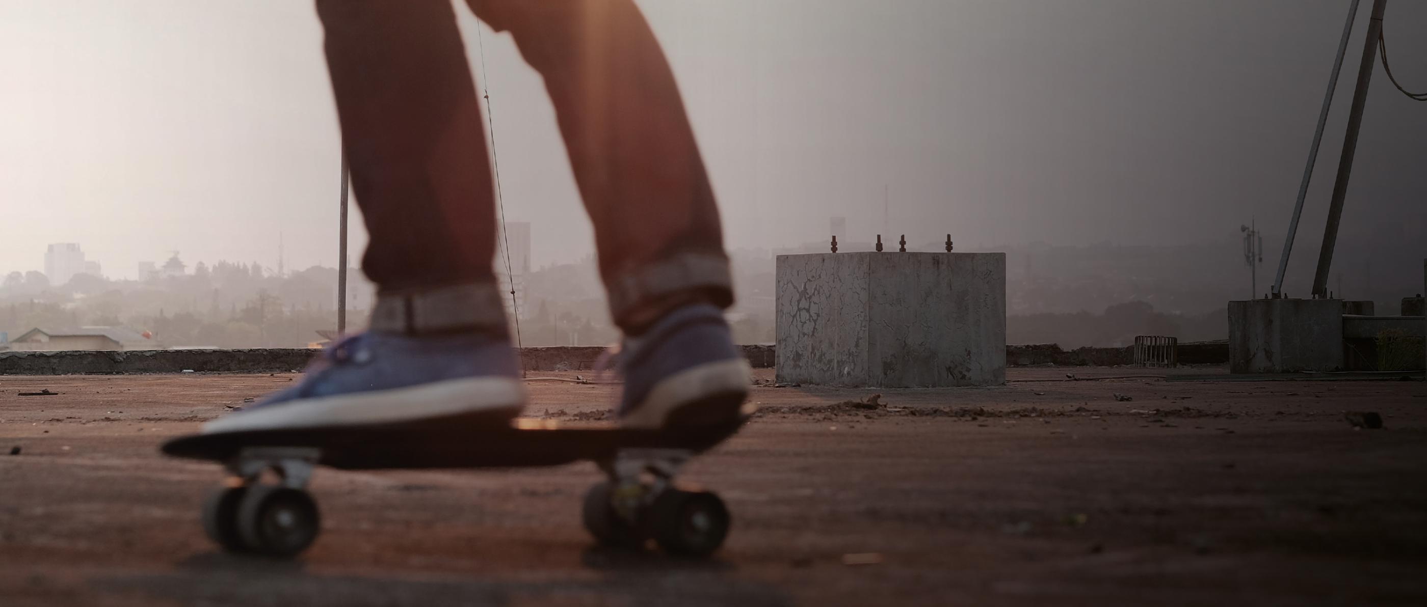 Ein Mensch mit Turnschuhen steht auf einem Skateboard.