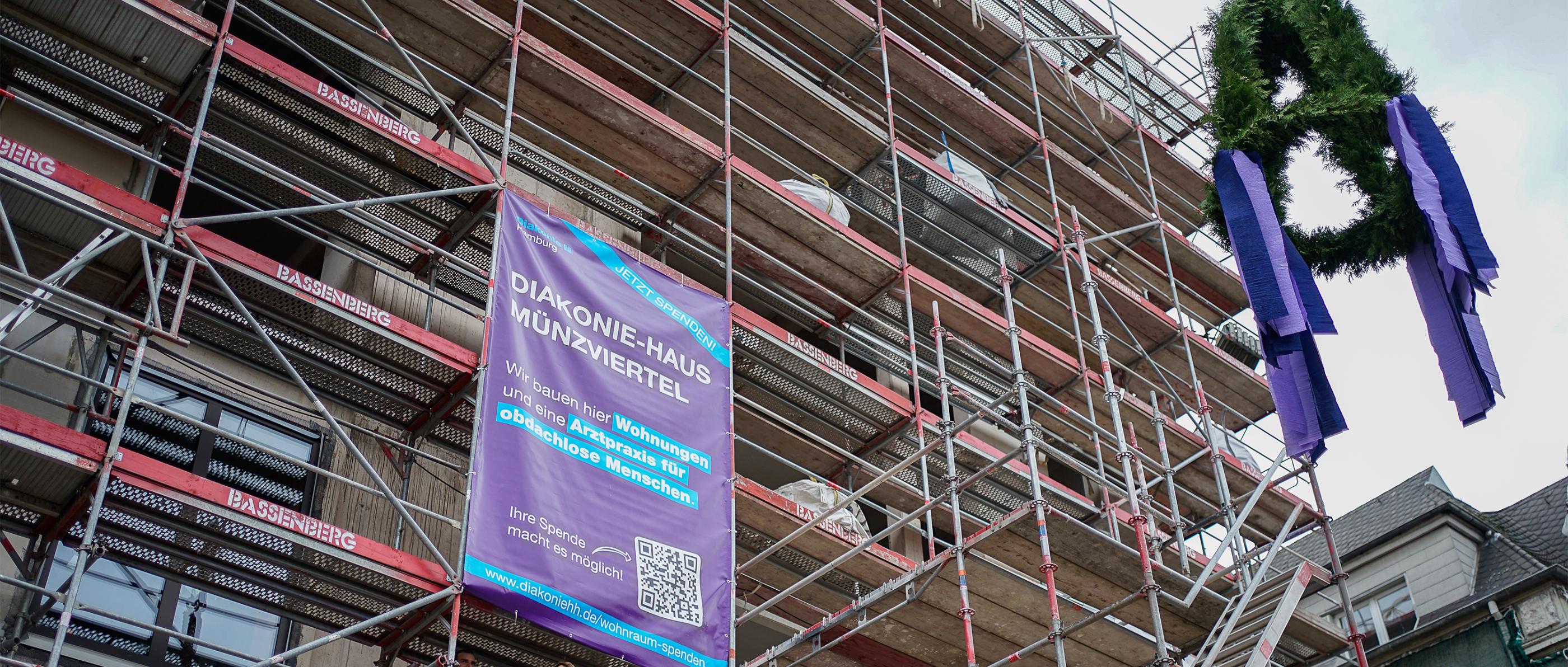 Ein Haus mit einem Gerüst, an dem eine Richtkrone hängt.