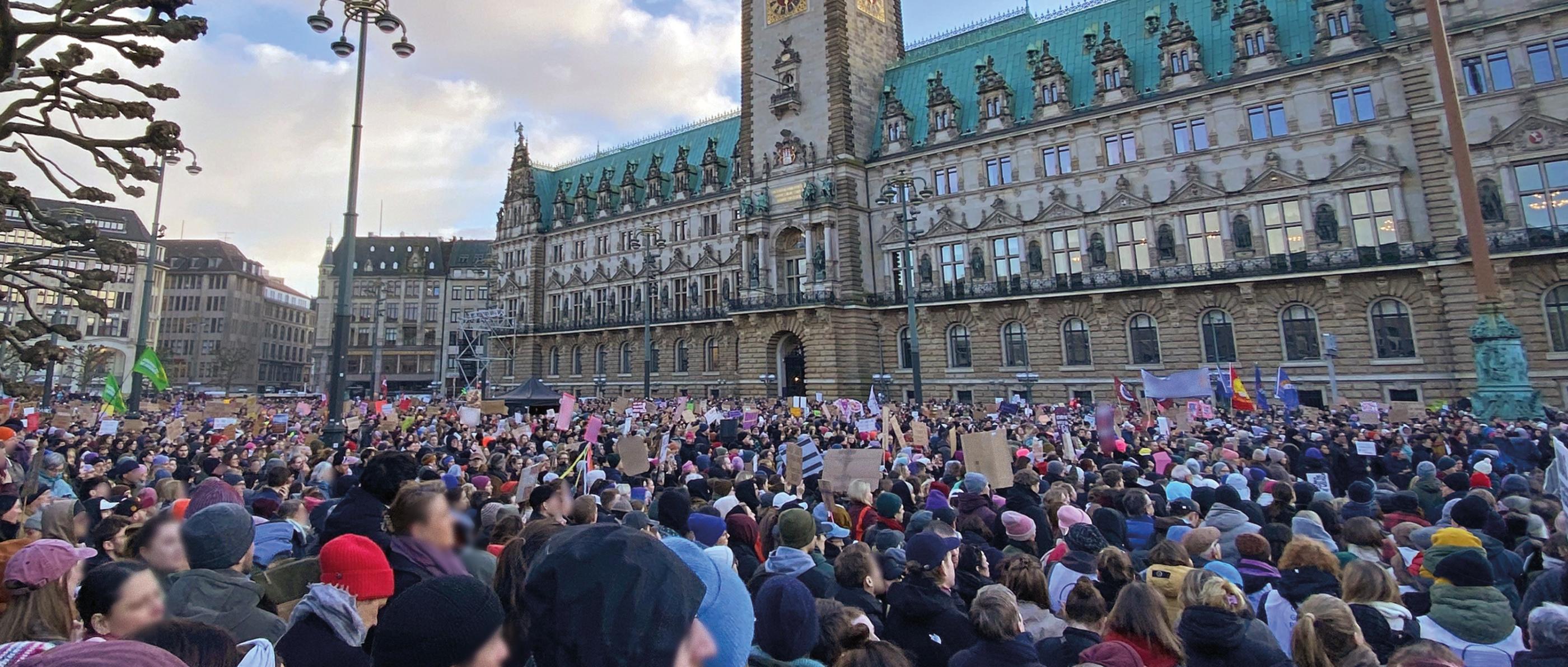 Menschen halten Plakate hoch vor dem Hamburger Rathaus
