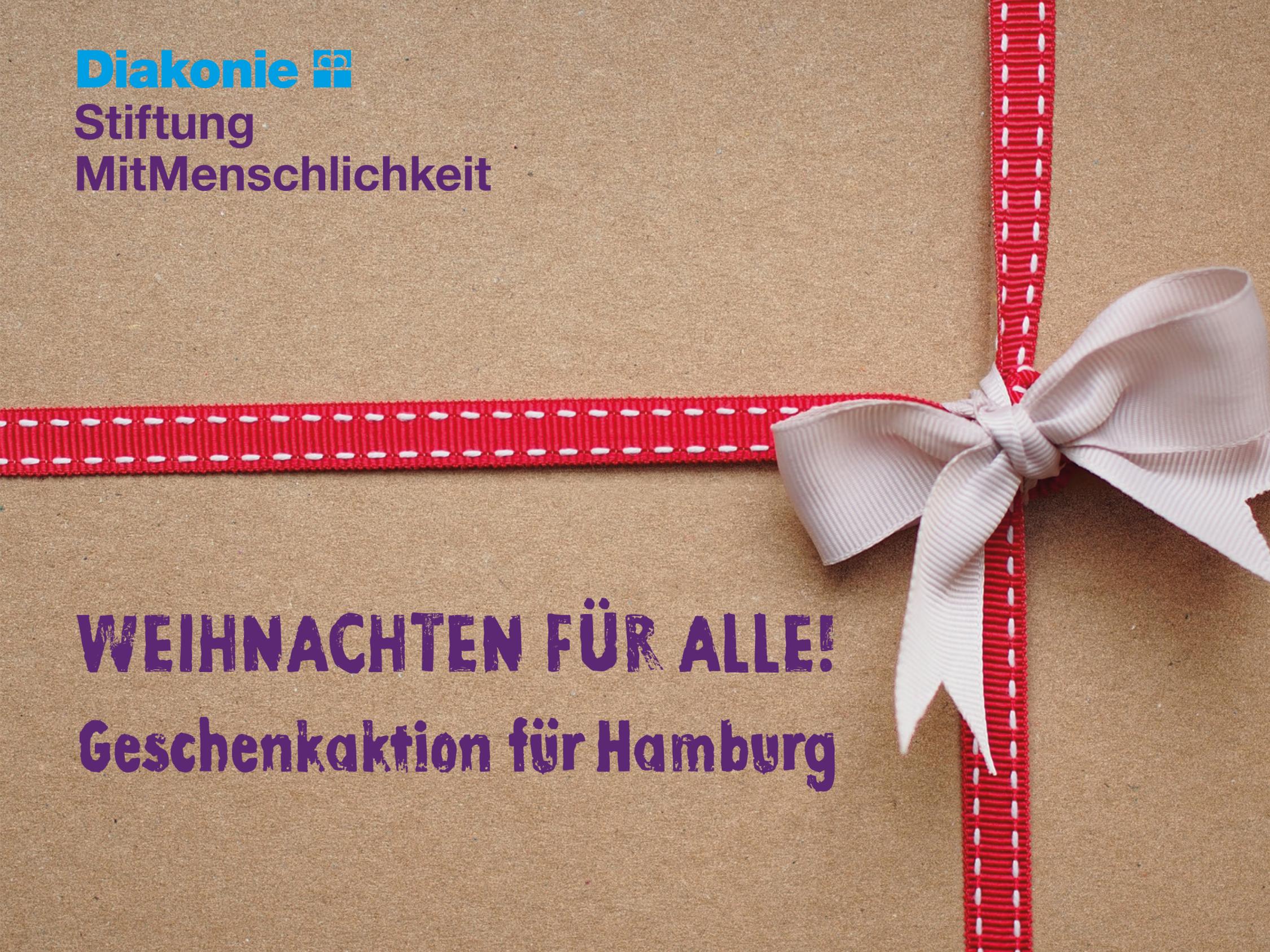 Um einen Karton ist rot-weißes Schleifenpapier geschlungen, darauf der Schriftzug 'Weihnachten für alle! Geschenkaktion für Hamburg'.