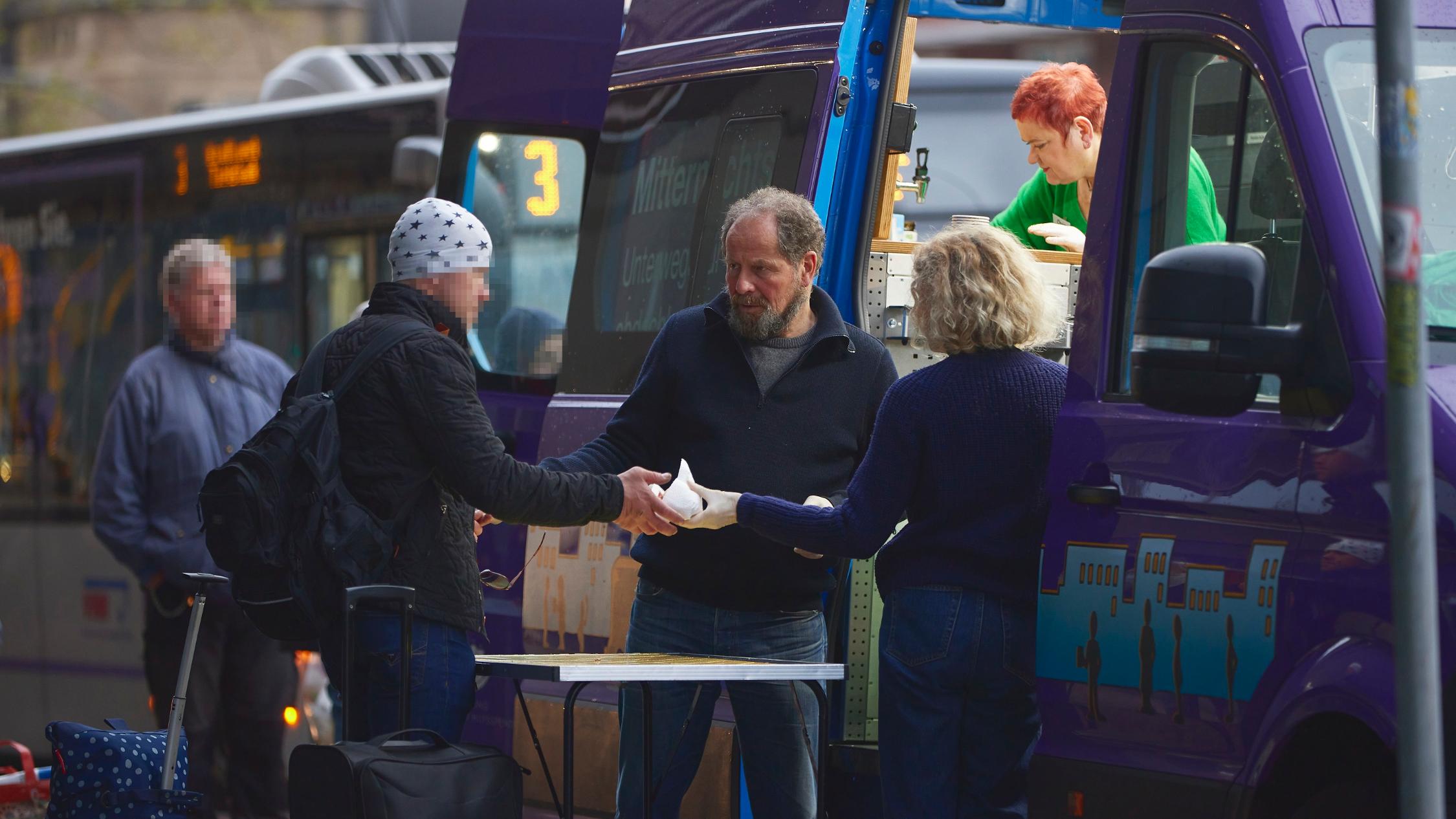 Freiwillige vom Mitternachtsbus geben Essen aus.