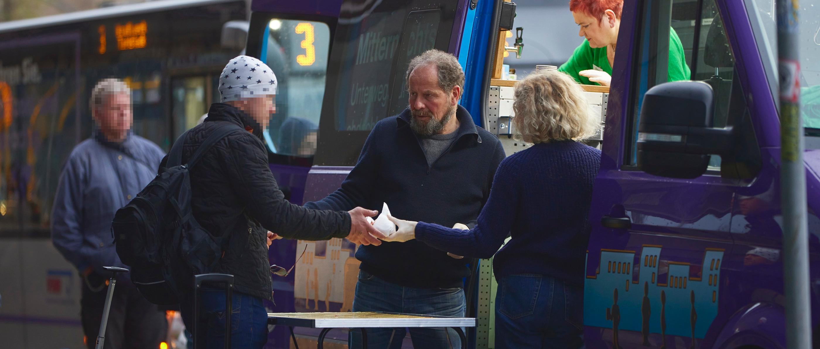 Freiwillige vom Mitternachtsbus geben Essen aus.