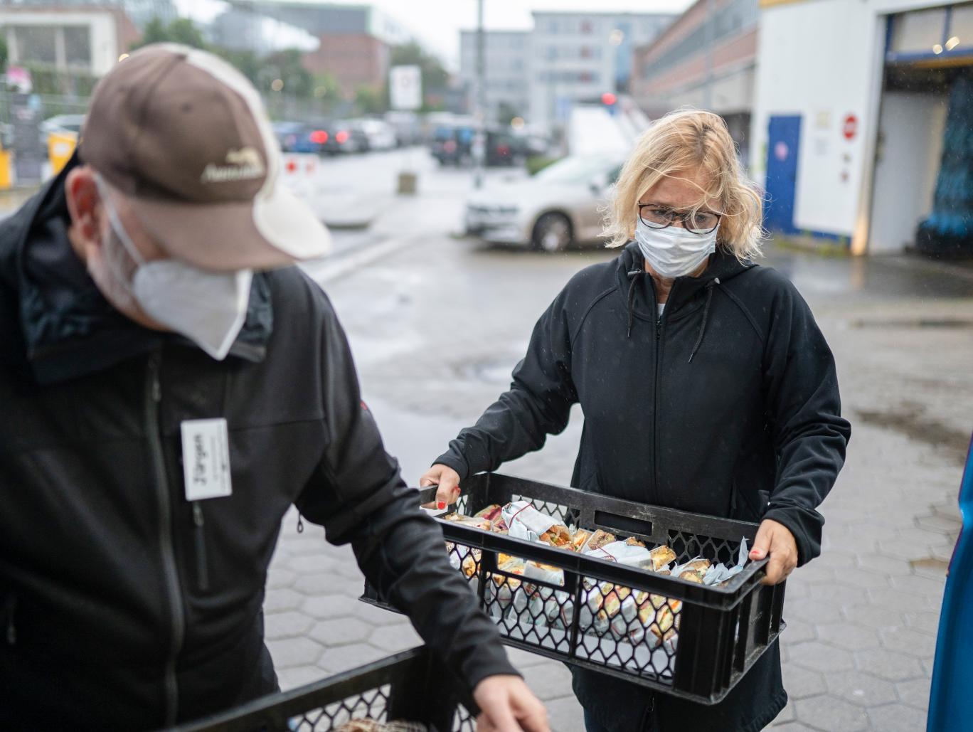 Eine Frau mit Mundschutz hält einen Korb mit Broten.