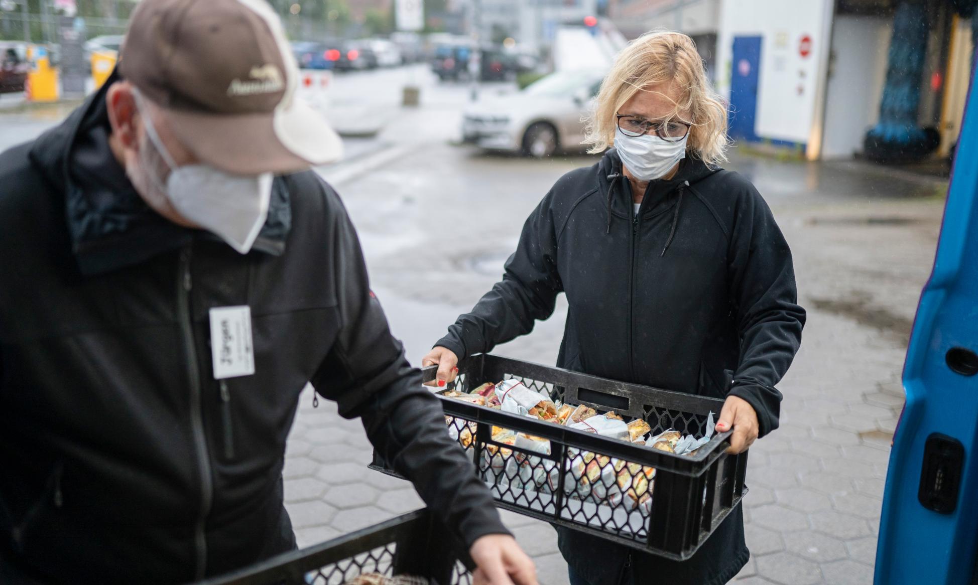 Eine Frau mit Mundschutz hält einen Korb mit Broten.
