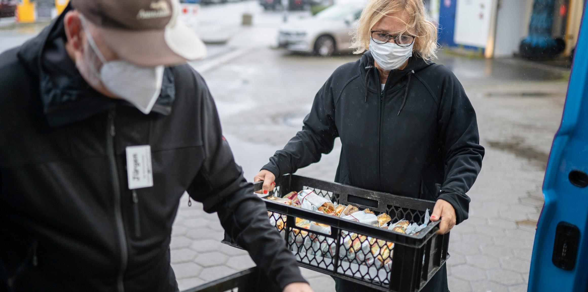 Eine Frau mit Mundschutz hält einen Korb mit Broten.