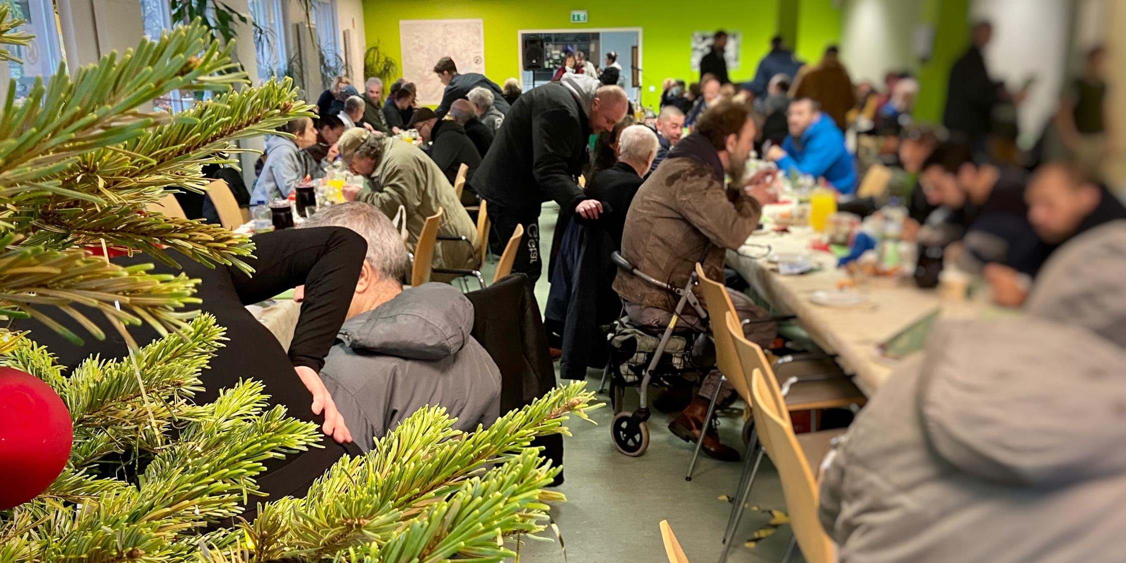 Obdachlsose sitzen beim Weihnachtsessen.