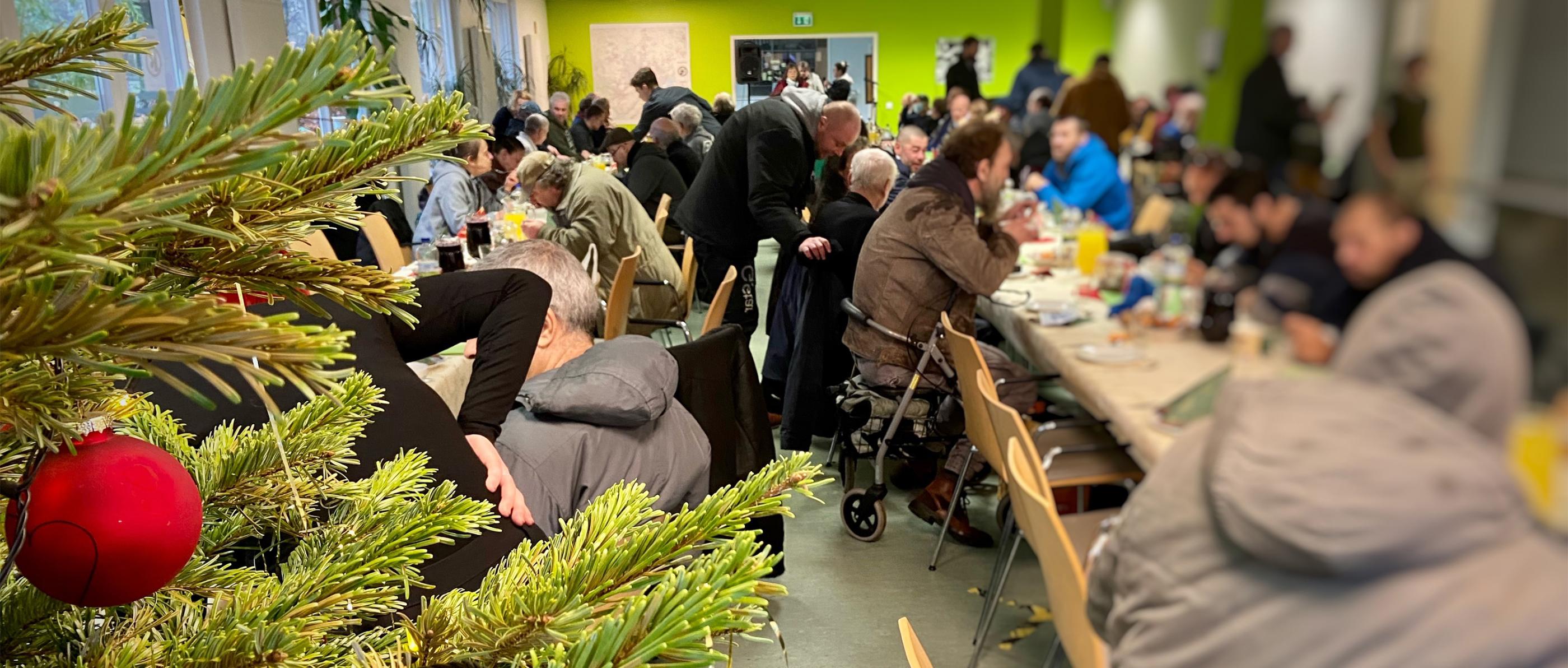 Obdachlsose sitzen beim Weihnachtsessen.